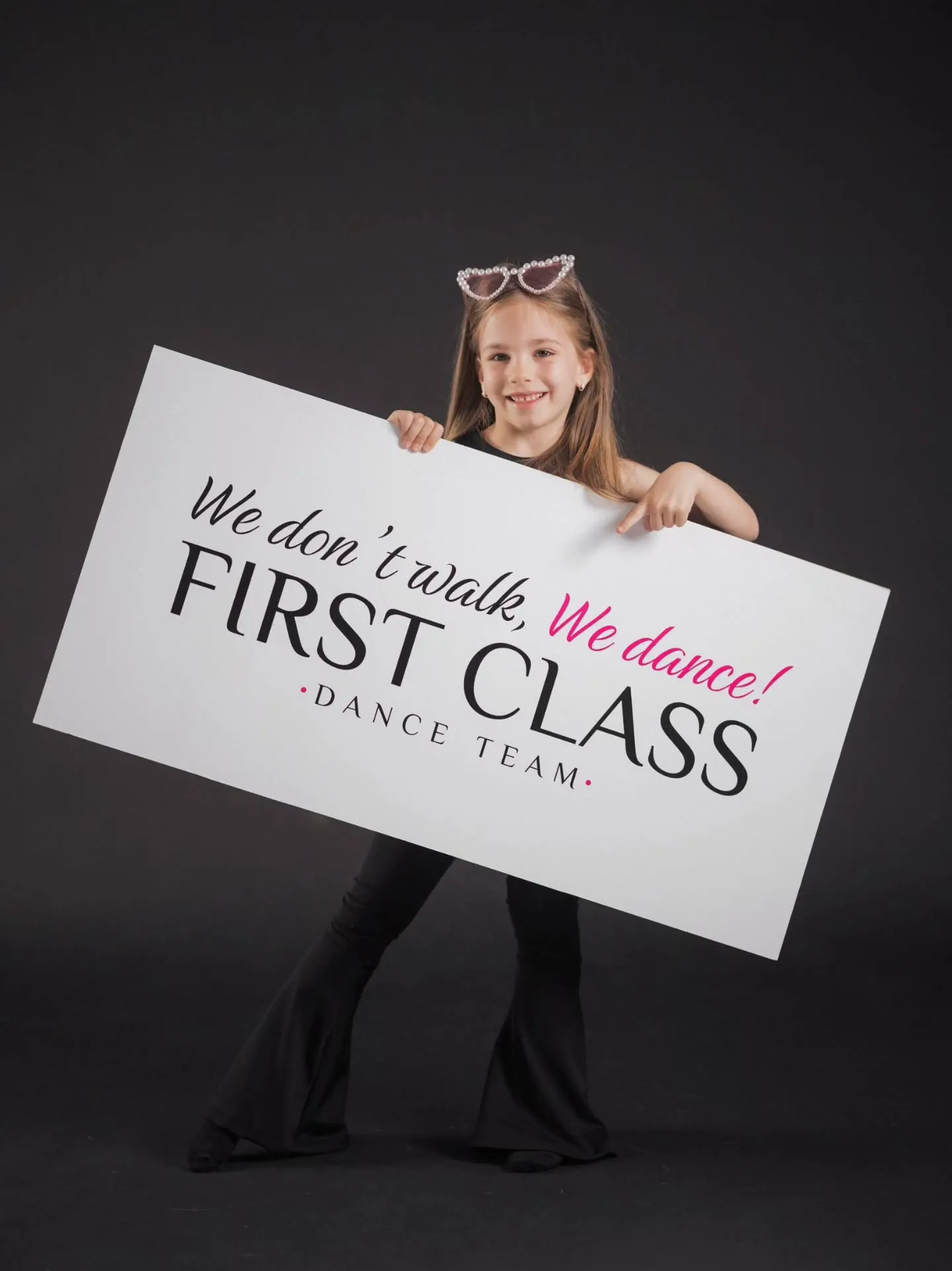 Mala plesačica drži tablu sa sloganom First Class Dance Team